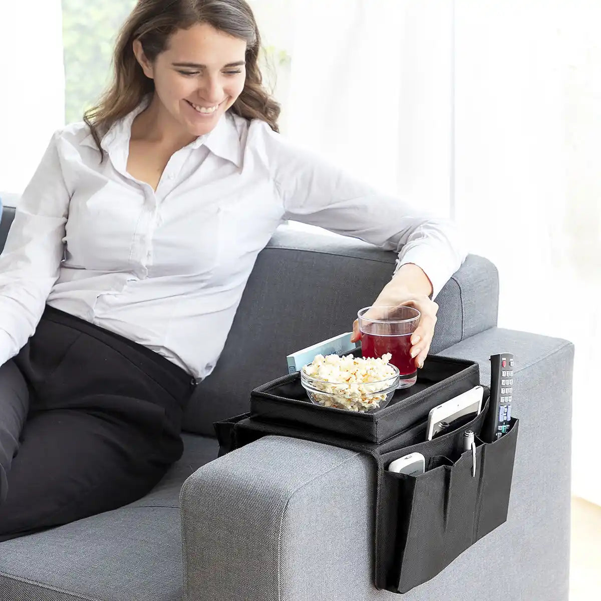 En dame som nyter popcorn og brus som er plassert på sofabrettet