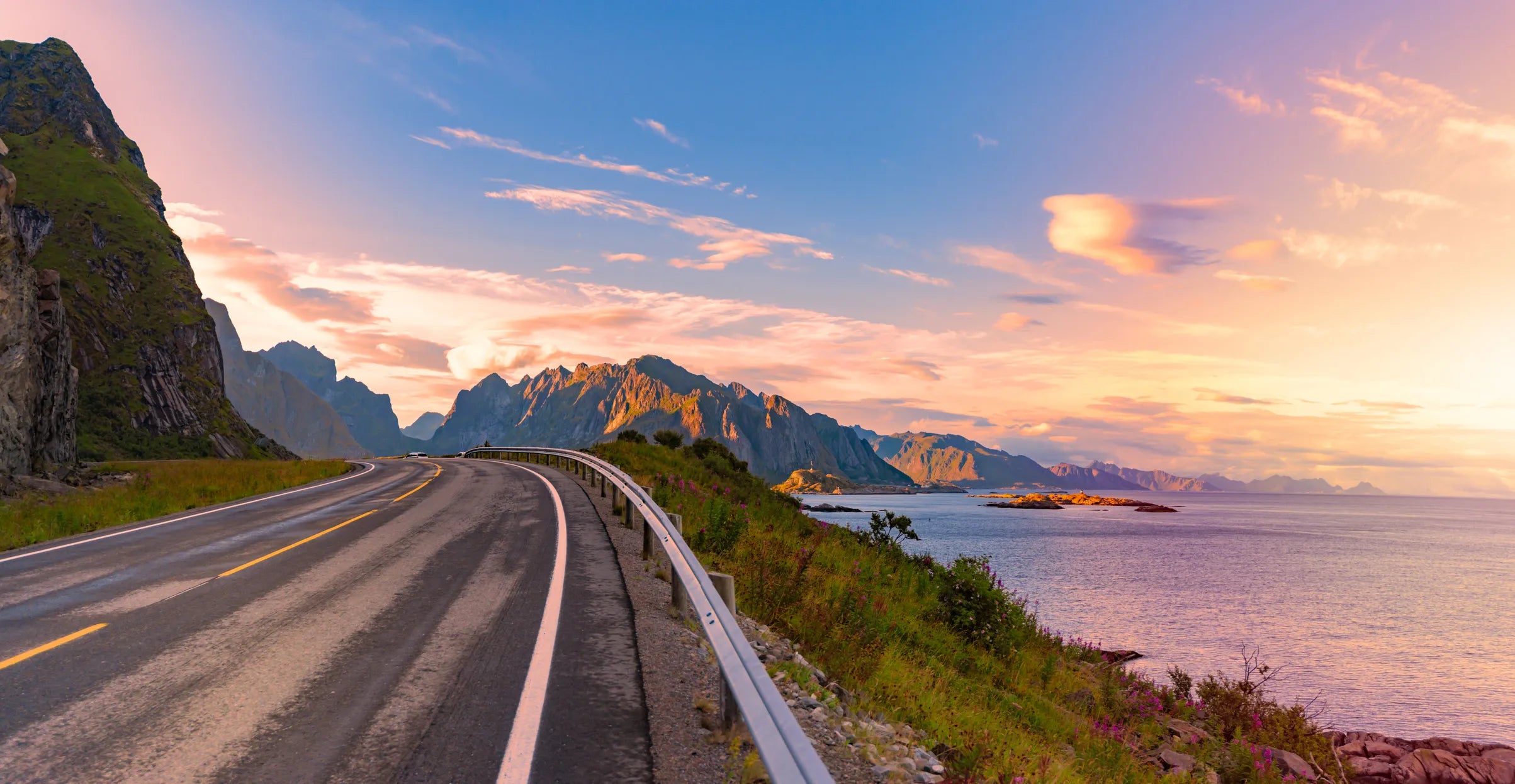 En vei i Lofoten i Nord-Norge med vakker utsikt mot fjell og hav.