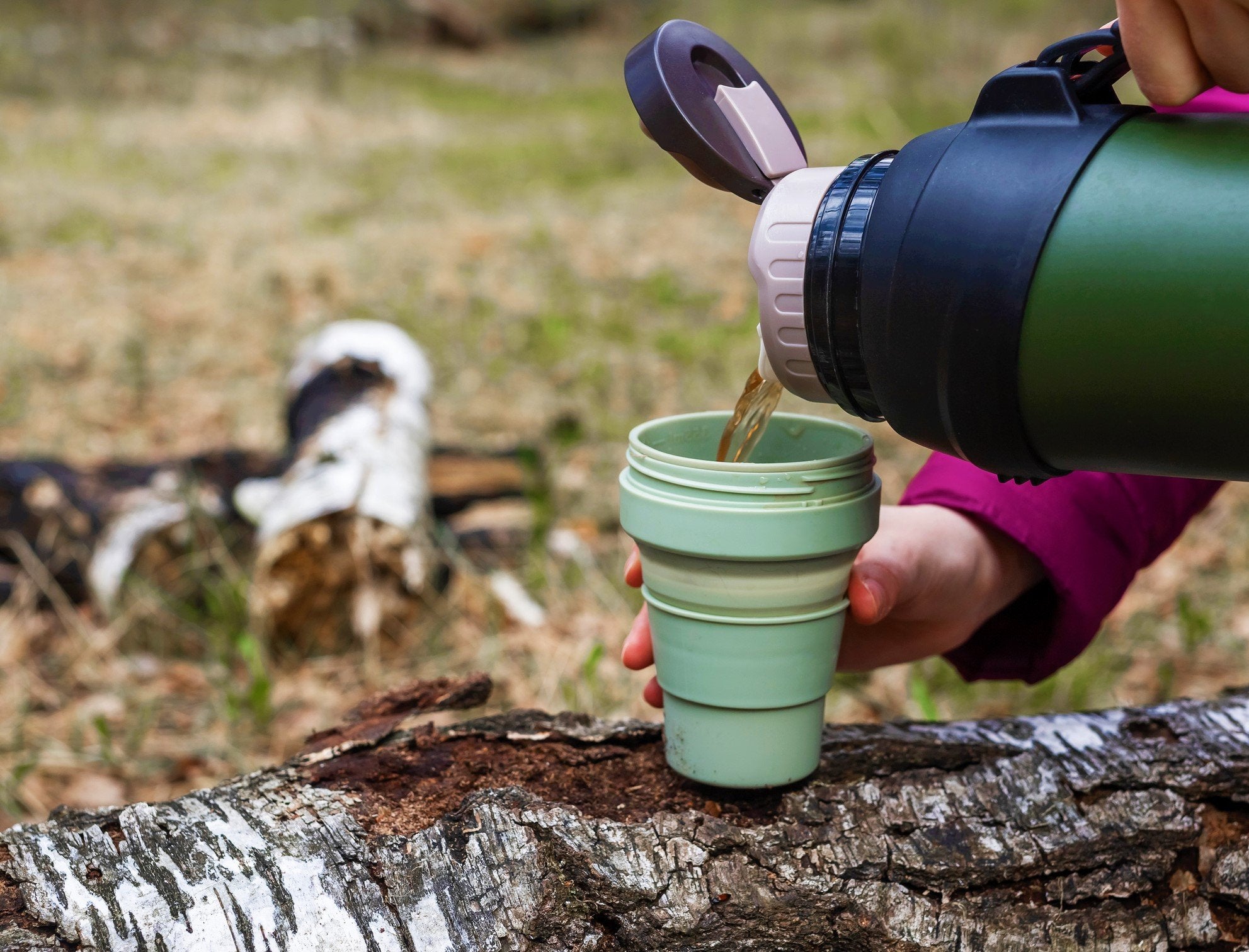 En person som nyter fersk og varm kaffe ute i naturen.