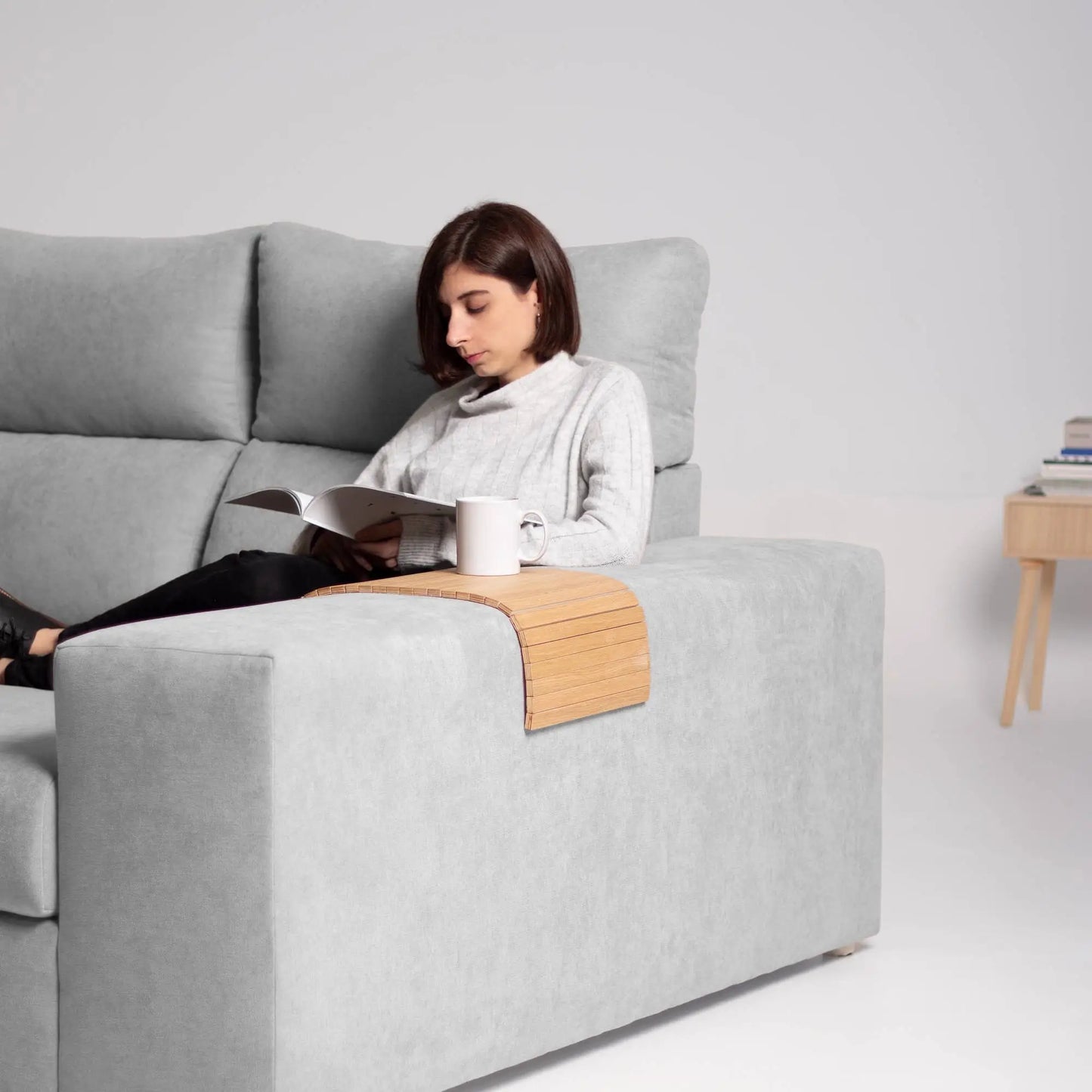 Ei dame som drikker en kopp te som ligger stabilt på sofabrettet