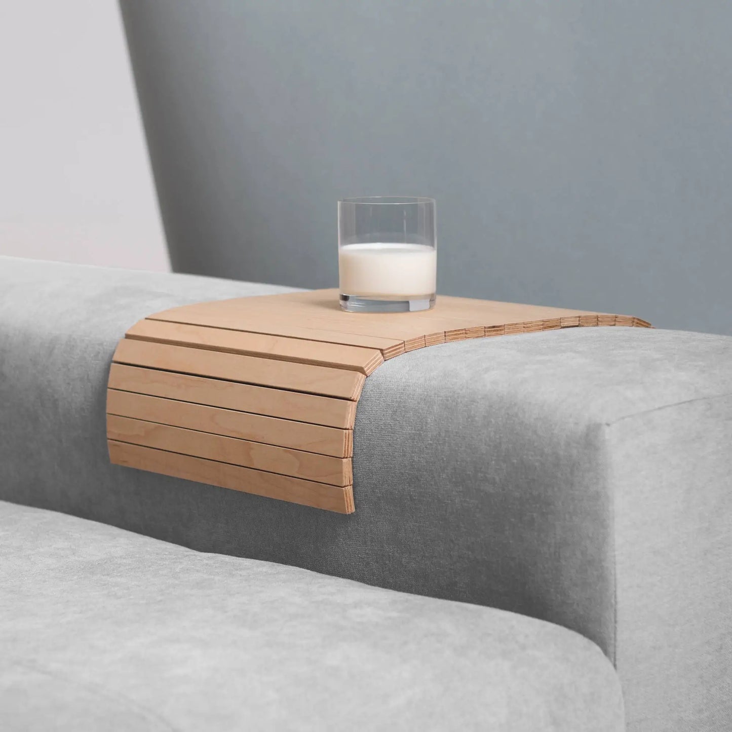 Armlenebrett i lønnetre farge med et glass melk på en sofa