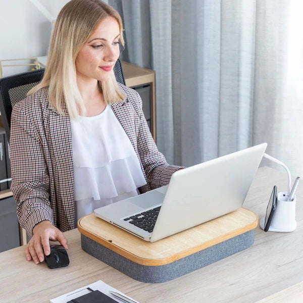 Ei dame som bruker det bærbare bordet på et kontor som støtte for sin laptop