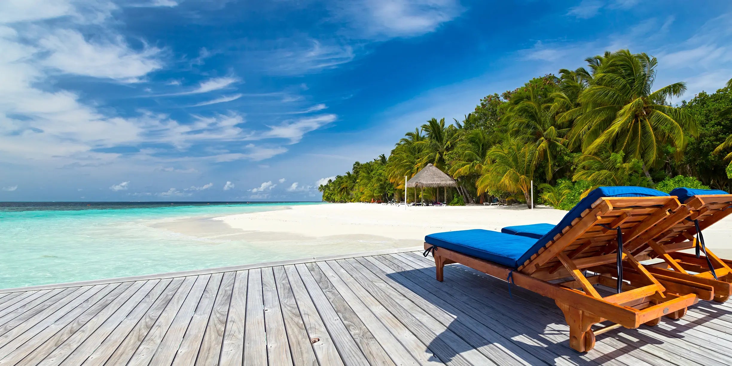 Solsenger på en platting på en tropisk øy med stranda og havet.