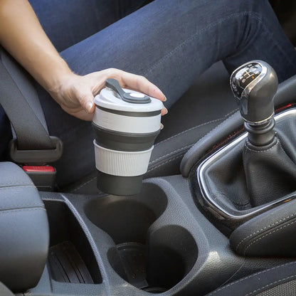 En dame som nyter sin morgenkaffe fra den smarte koppen i en bil