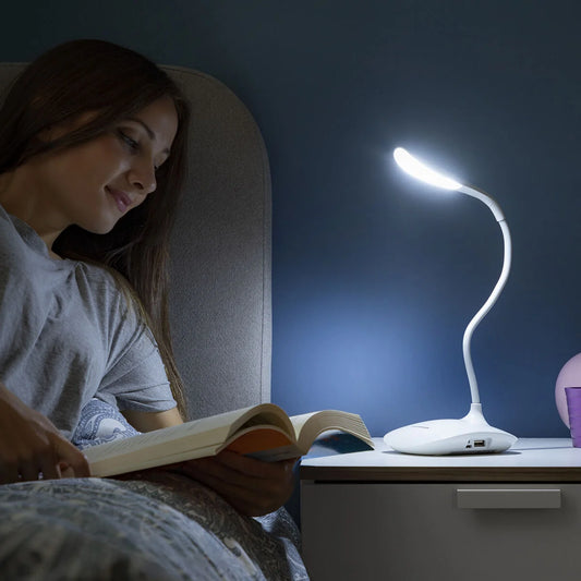 En dame som leser en bok og bruker den trådløse oppladbare bordlampen