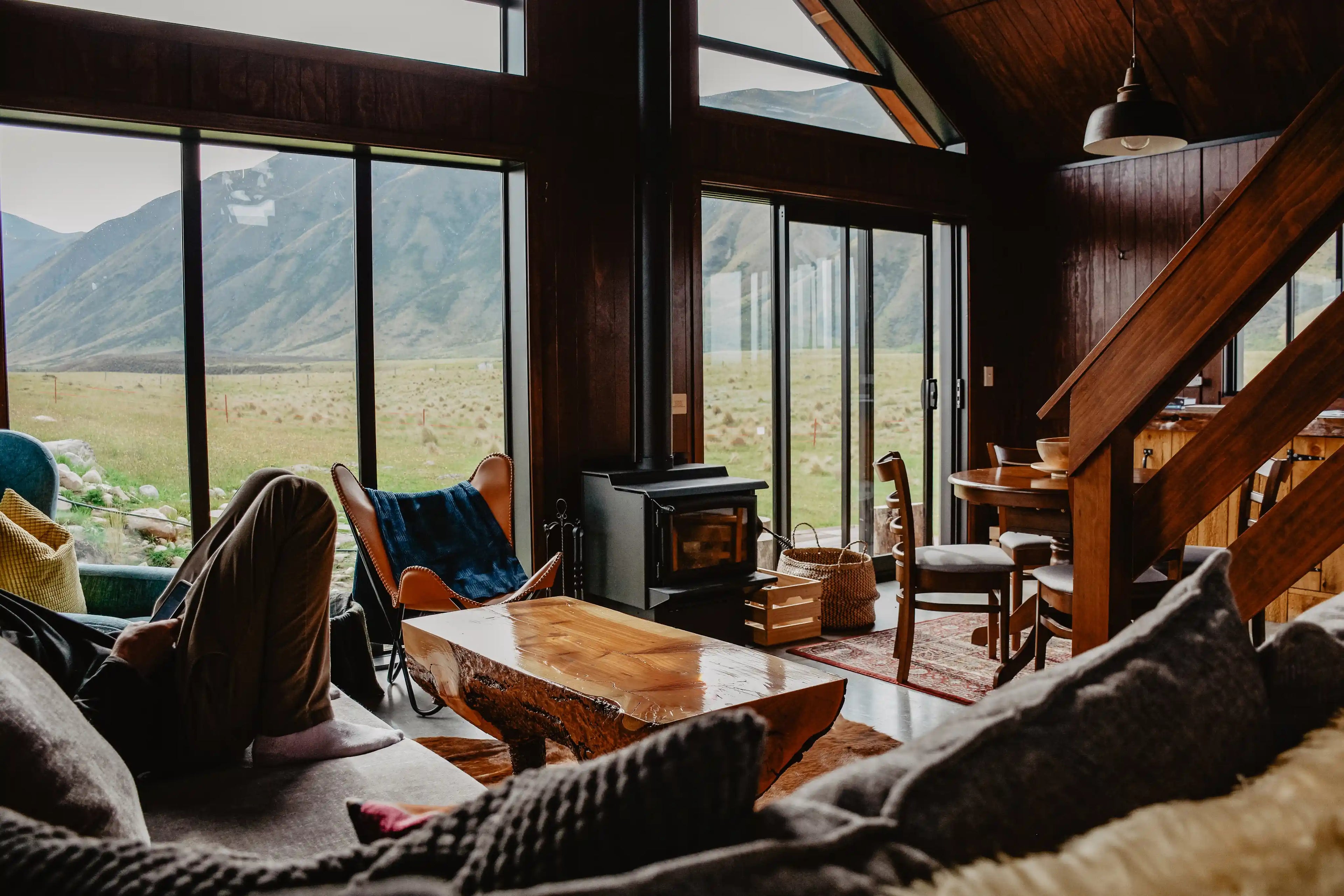En mann sitter på en sofa i en hytte midt i naturen med en vakker utsikt.