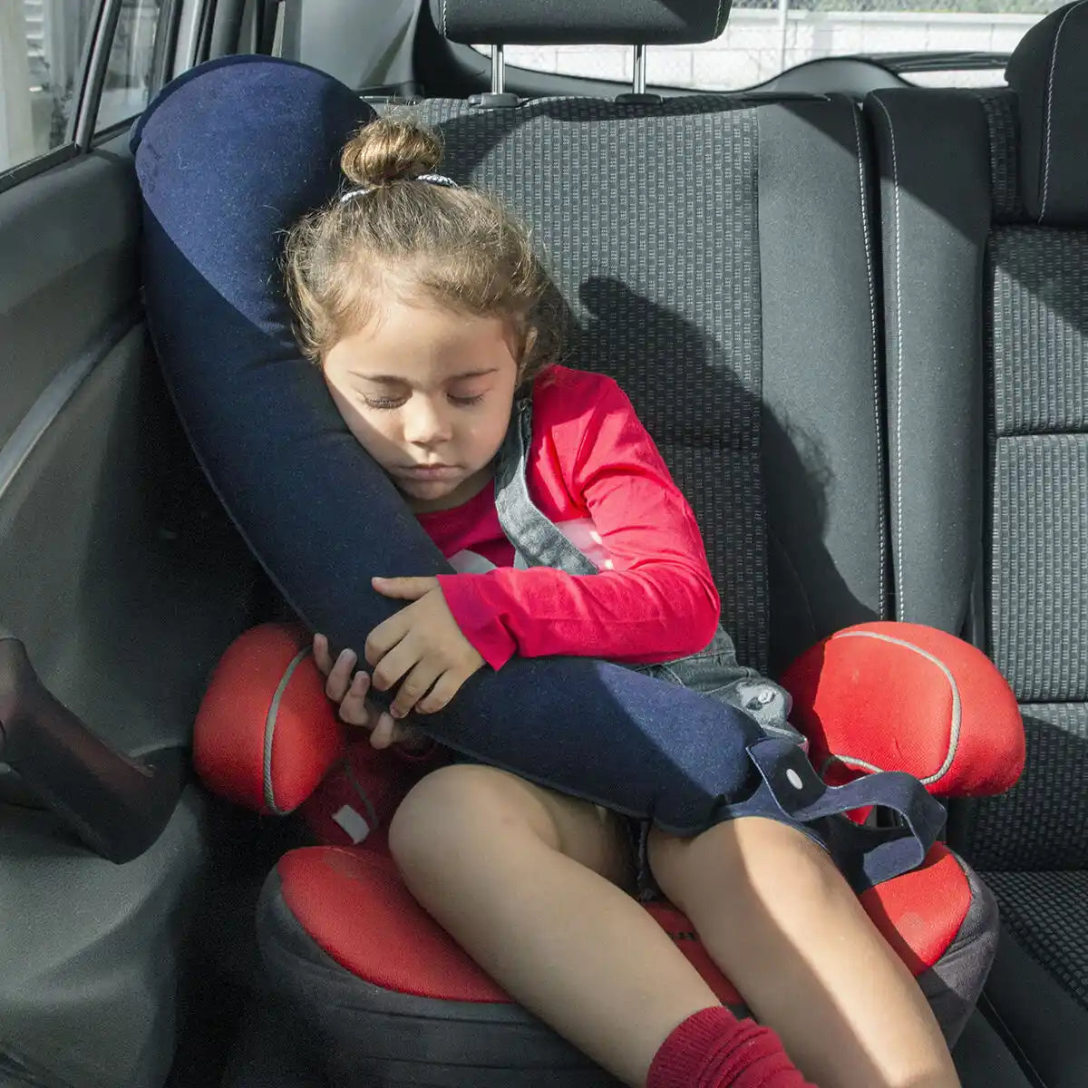 Et barn som sover i bilen på den oppblåsbare puten