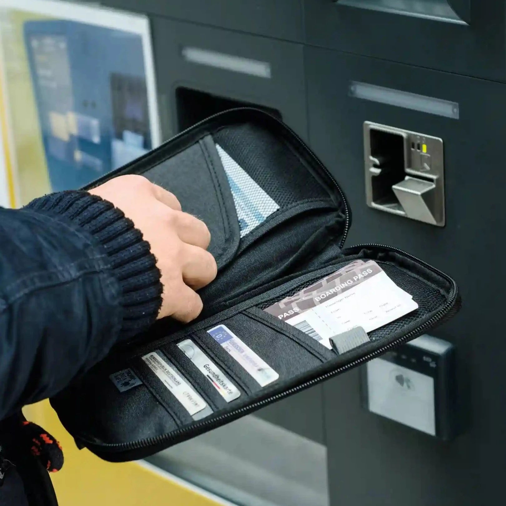 En mann med en svart reiselommebok som skal bruke en ATM